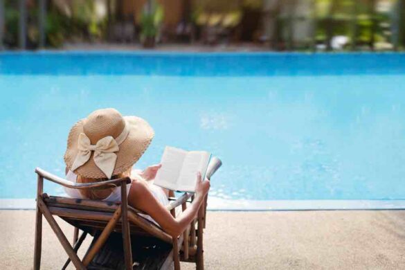 woman reading book poolside