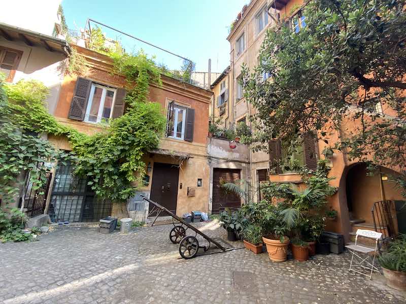 Arco degli acetai, scenic courtyard in Rome with pretty homes and overflowing plants. 