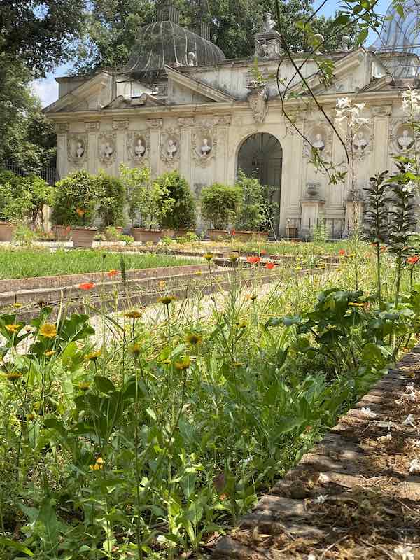 Flower garden in Villa Borghese with elaborate building in the background
