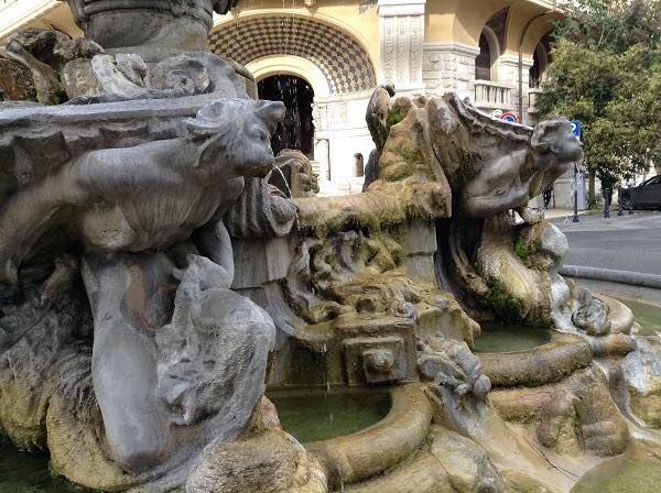 Close up of Fountain of the Frogs in the Coppede District in Rome with sculptures of faces spitting out water and small carved frogs