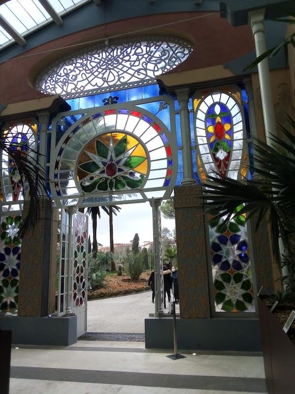 Inside of Moorish Greenhouse in Villa Torlonia, Rome, with colorful stained glass windows and palms