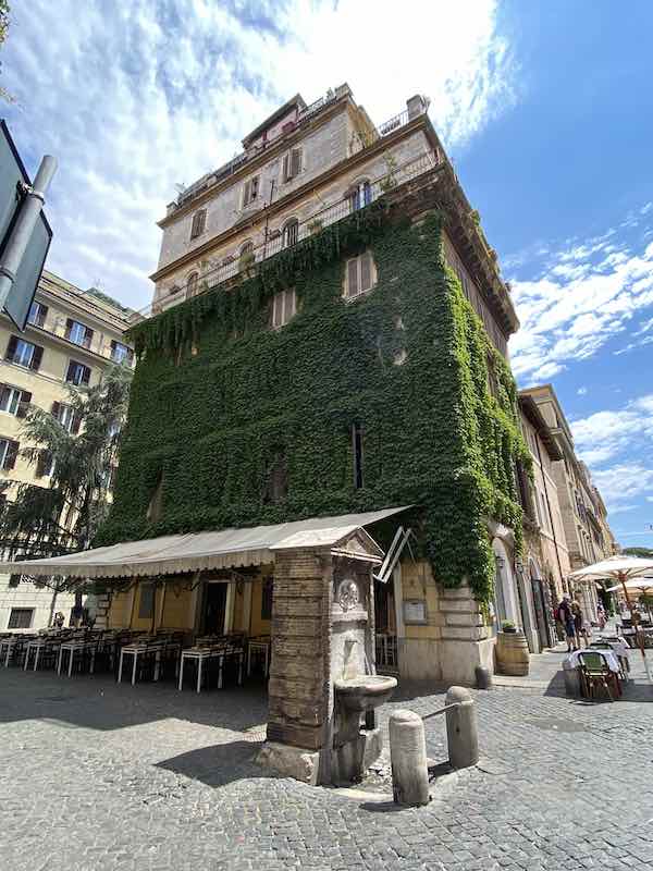 House covered in greenery with fountain in the foreground in Rome Borgo Pio