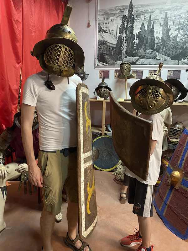 My husband and tween son trying on Roman army gear during a gladiator class in Rome