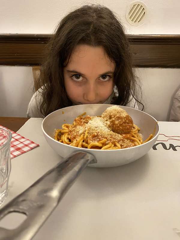 my daughter in a Rome restaurant with pasta and meatballs 